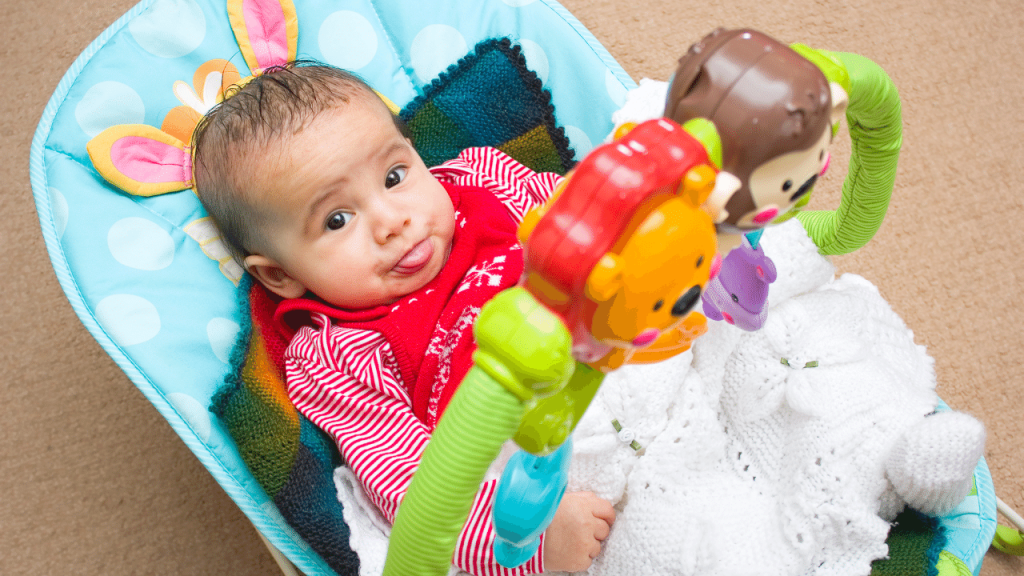 newborn baby sticking out his tongue in a bouncer